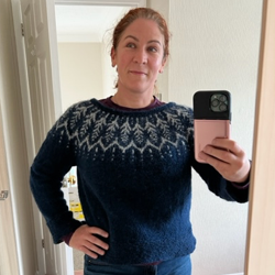 A mirror selfie of Insomnia Patient Leader Tracy Hannigan wearing a knitted navy blue fair isle sweater with white decorative design.