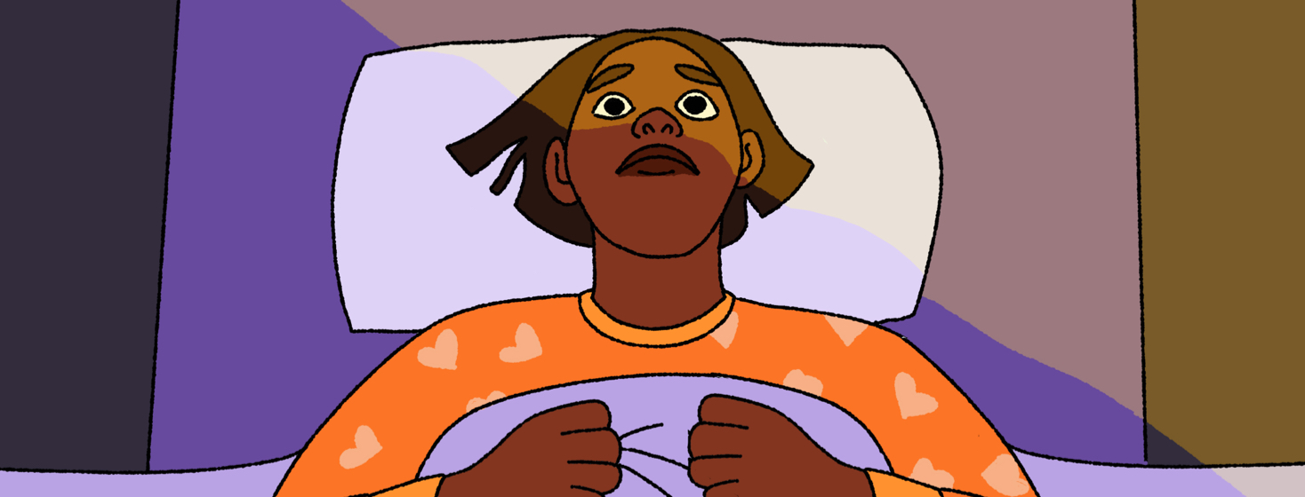 A latina woman lying awake in bed with light across her forehead, clutching her bedcovers. Her eyes are wide open, alert, and pointed up to the ceiling with a frown.
